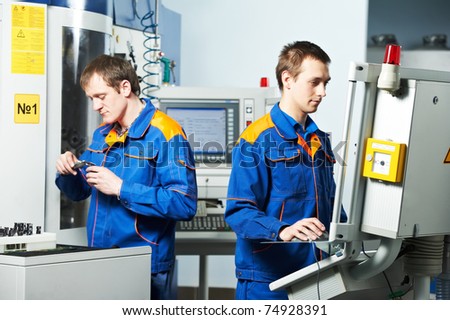 mechanical technicians working at cnc milling machine center in tool workshop