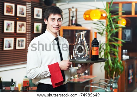 handsome man waiter in uniform with tray and wine at restaurant
