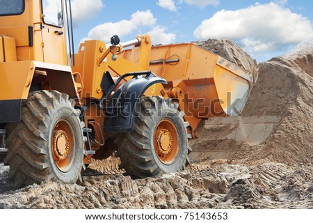 Wheel loader machine unloading sand at eathmoving works in construction site