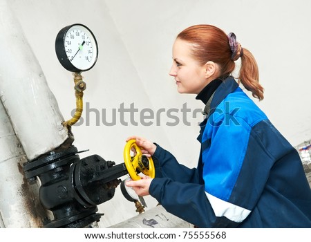 woman engineer using valve of heating system equipment in a boiler room