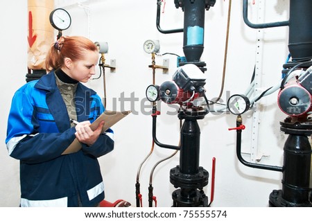 woman engineer checking technical data of heating system equipment in a boiler room