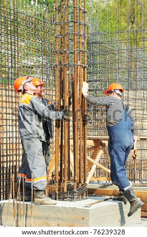 builder workers installing metal rods bars into framework reinforcement for concrete pouring at construction site