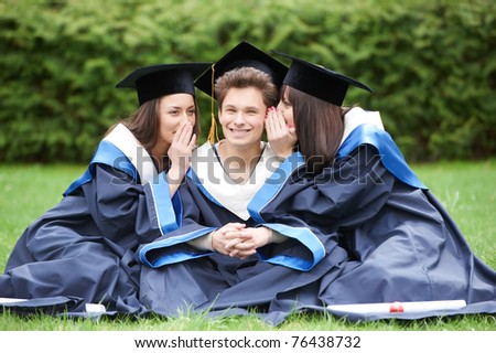 group of three graduate whispering students in the park cheerful and happy