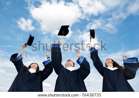 three graduate students tossing up hats over blue sky