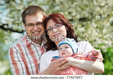 Portrait of happy three person smiling family standing outdoors over spring bloom