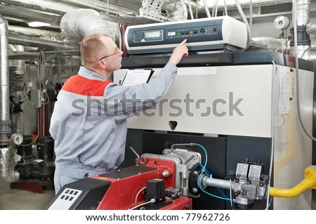 maintenance engineer checking technical data of heating system equipment in a boiler house