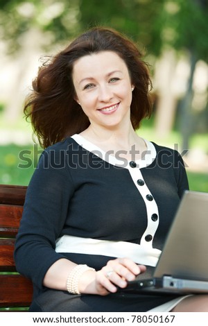 cheerful smiling middle age woman working on a laptop computer outdoors