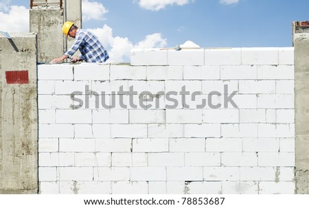 construction mason worker bricklayer making a brickwork with trowel and cement mortar