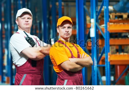 young workers men in uniform in front of warehouse rack arrangement stillages