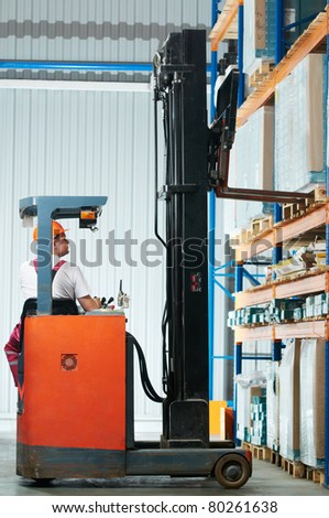 Warehouse worker distributing goods in a storehouse with forklift truck loader stacker