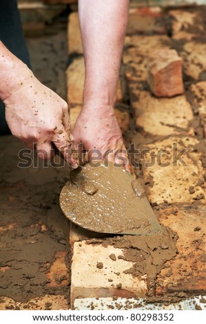 Mason hands at bricklaying works with trowel and clay brick blocks