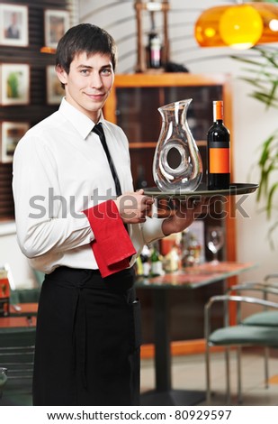 handsome man waiter in uniform with tray and wine at restaurant