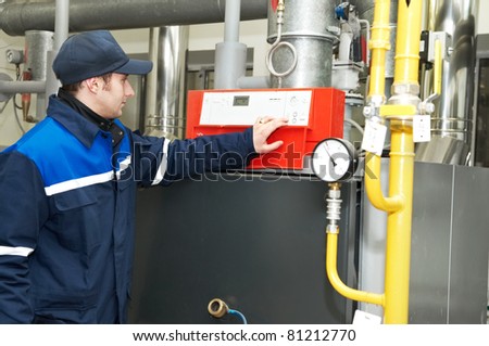 maintenance engineer checking technical data of heating system equipment in a boiler house
