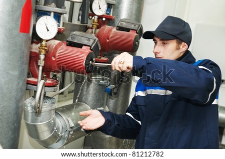 maintenance engineer repairing water pump of heating system equipment in a boiler house