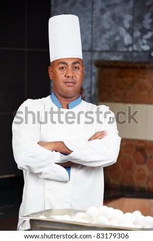cheerful arab chef man in uniform standing at kitchen
