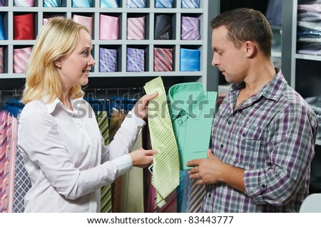 Young couple choosing shirt and necktie during clothes shopping at sales store