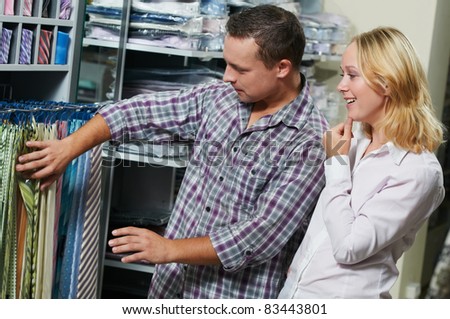 Young couple choosing necktie during clothes shopping at sales store