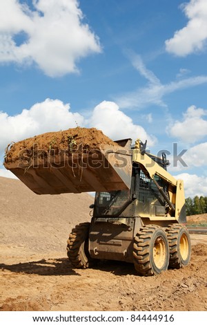 skid steer loader moving sand soil at construction area outdoors