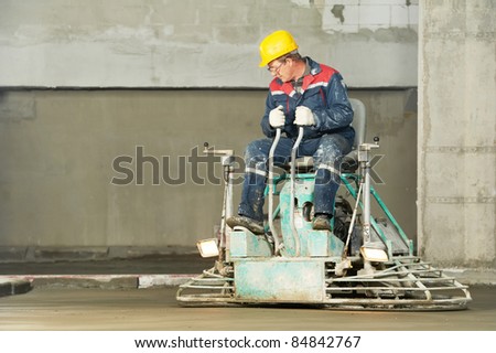 Worker trowelling and finishing of concrete by special construction equipment
