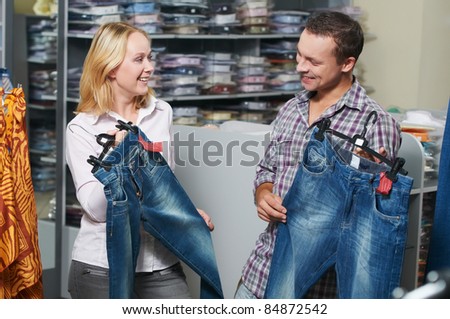 Young couple choosing jeans during clothes shopping at sales store
