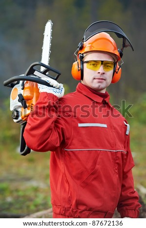 Lumberjack Worker in protective safety work wear With Chainsaw at Forest