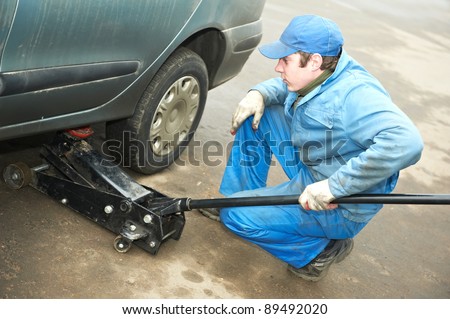 mechanic repairman making tyre fitting by using jack for car lifting