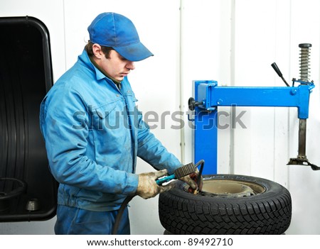mechanic repairman making tyre fitting with compressed air
