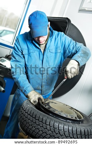 mechanic repairman making tyre fitting screwing out a wheel nipple