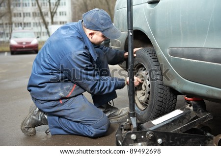 mechanic repairman making tyre fitting by using jack for car lifting