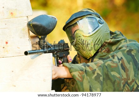 paintball sport player wearing protective mask aiming gun with head shot by paint spot