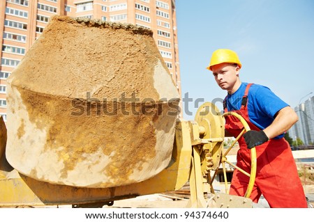 builder laborer man working with front of concrete cement mixer at construction site