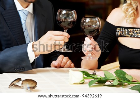 Man and girl hand drinking wine at street cafe on a date with flower on table