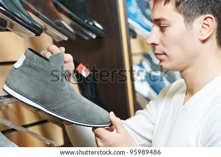 Young man choosing shoes during footwear shopping at shoe shop