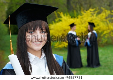 female smiling graduate student in the spring park after finishing education with diploma