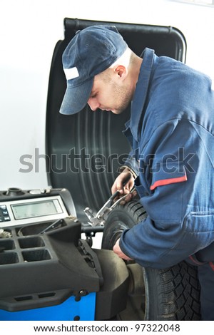 mechanic repairman at car tyre fitting and balancing adjustment using special equipment