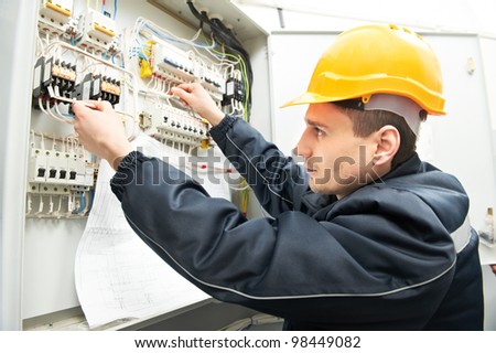 One electrician builder at work with assembly drawing inspecting high voltage power electric line distribution fuseboard