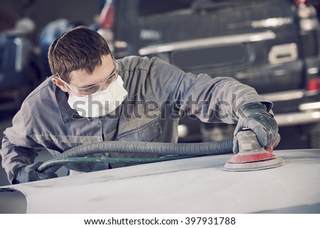 auto repairman grinding autobody bonnet