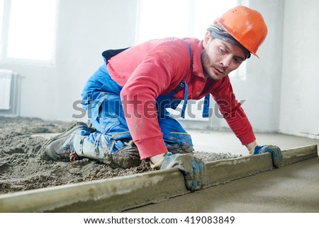 worker screeding indoor cement floor with screed