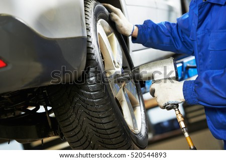 auto mechanic screwing car wheel by wrench