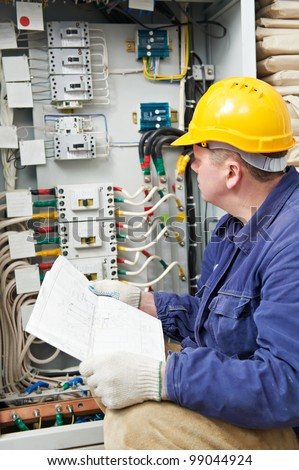 One electrician builder at work with assembly drawing inspecting high voltage power electric line distribution fuseboard