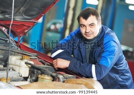 Smiling happy mechanic technician worker at car maintenance repair service station