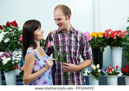 Man presenting flower to girl at shop on a date