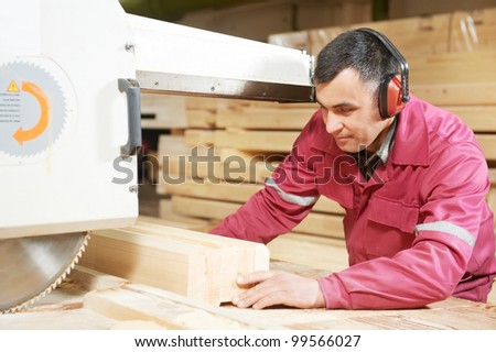 Closeup process of carpenter worker with circular saw machine at wood beam cross cutting during furniture manufacture