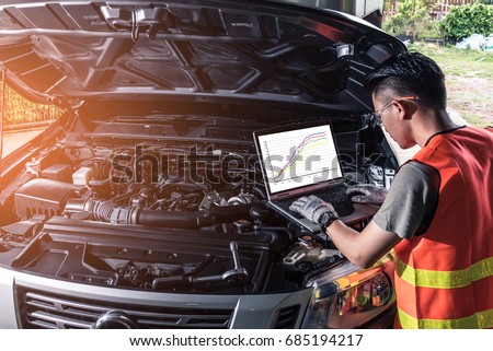 The asian technician analyze the car\'s engine graph on laptop computer in the garage. the concept of automotive, repairing, mechanical, vehicle and technology.