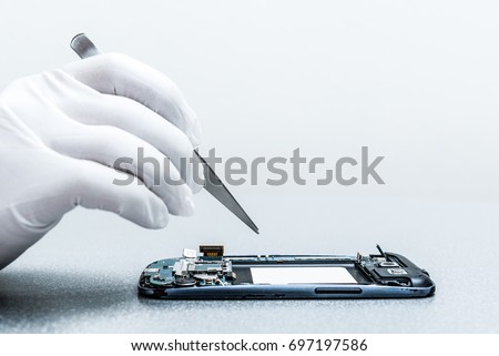 The asian technician repairing the smartphone\'s motherboard in the lab with copy space. the concept of computer hardware, mobile phone, electronic, repairing, upgrade and technology.