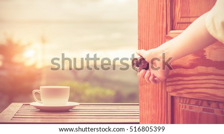 Women hand open door knob or opening the door view coffee espresso on wood table nature background in garden,warm tone