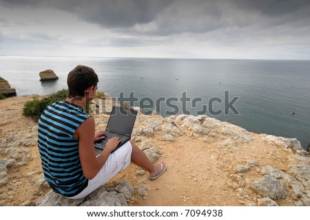 man working on portable pc in the coast