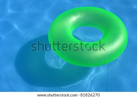 An inflatable green plastic buoy in a shiny blue swimming pool