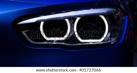 New aggressive headlight by night. Car detail. The front lights of the blue car, in sports car developed by model 2016. Car\'s light.