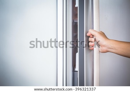 Abstract hand a young man is opening a refrigerator door